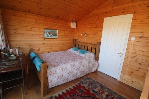 a bedroom with a bed in a wooden cabin at Maid Marian's Lodge, Nottinghamshire in East Bridgford