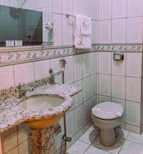 a bathroom with a sink and a toilet at Hotel Cataguases in Cataguases