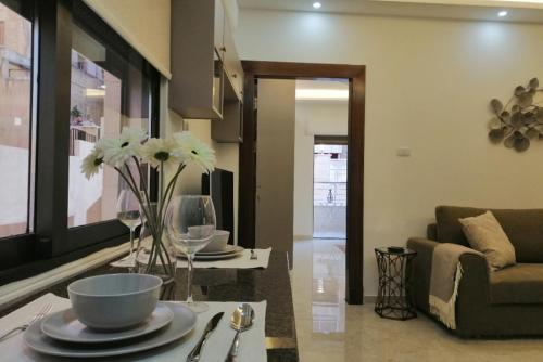 a living room with a table with plates and flowers on it at Executive Apartments in Amman
