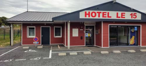 a red hotel with a hotel sign in a parking lot at Hôtel Le 15 Périgueux in Coulounieix-Chamiers