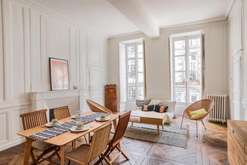 un salon avec une table et des chaises en bois dans l'établissement L'Alcôve - Volume et Elégance en coeur de ville, à Rennes