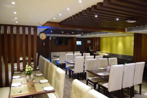 uma sala de jantar com mesa e cadeiras e um relógio em Thiviyam Airport Hotel em Chennai