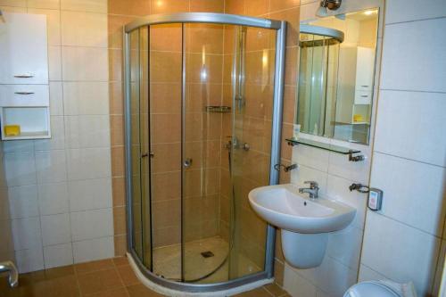La salle de bains est pourvue d'une douche et d'un lavabo. dans l'établissement Апартамент в Обзор Бийч Резорт на първа линия с директен достъп до плажа!, à Obzor