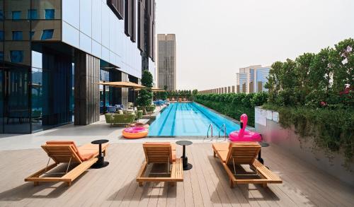 a swimming pool with lounge chairs and a pool noodle pool at Revier Hotel - Dubai in Dubai