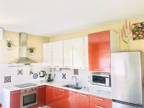 a kitchen with red cabinets and a white refrigerator at ATTICO IN FIERA apartment in Bologna
