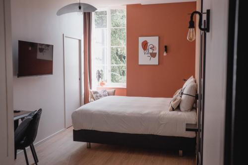 a bedroom with orange walls and a bed and a window at Hôtel-Restaurant Villa Métis in Les Herbiers