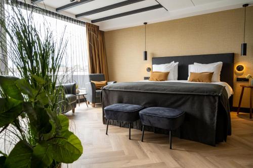 a bedroom with a large bed with two chairs at Van der Valk Cuijk - Nijmegen in Nijmegen