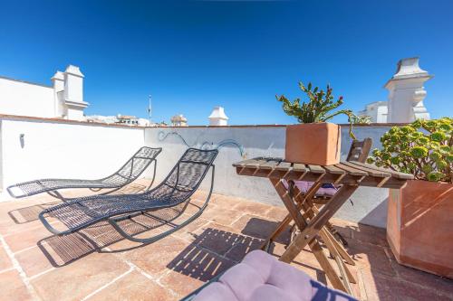 a patio with chairs and a table and a potted plant at La Casa de la Favorita in Tarifa