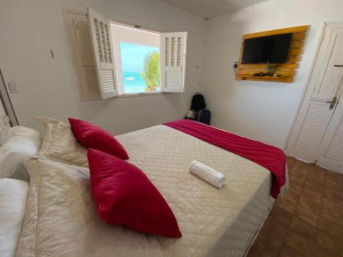 a bedroom with a bed with red pillows and a window at Barra lounge in Maragogi