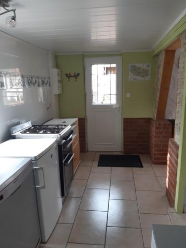 a kitchen with a stove top oven next to a door at gîte le voyageur in Tours-en-Vimeu