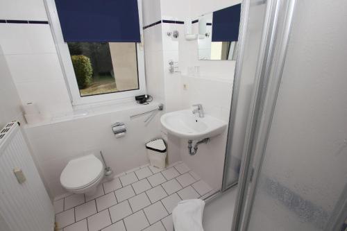 a white bathroom with a toilet and a sink at F-1010 Strandhaus Mönchgut Bed&Breakfast DZ 23 Terrasse, strandnah, inkl Frühstück in Lobbe
