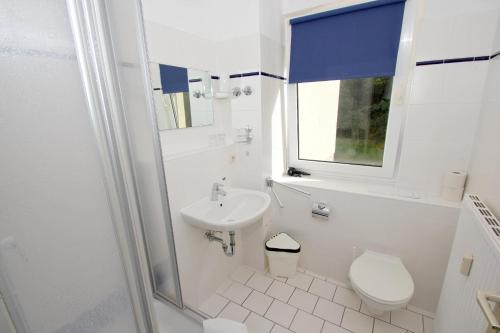 a white bathroom with a toilet and a sink at F-1010 Strandhaus Mönchgut Bed&Breakfast DZ 26 Garten, strandnah, inkl Frühstück in Lobbe