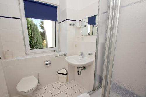 a white bathroom with a toilet and a sink at F-1010 Strandhaus Mönchgut Bed&Breakfast DZ 28 Terrasse strandnah, inkl Frühstück in Lobbe