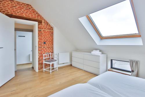 a bedroom with a skylight and a brick wall at La Cense de Baudecet - Le Corps de Logis in Gembloux