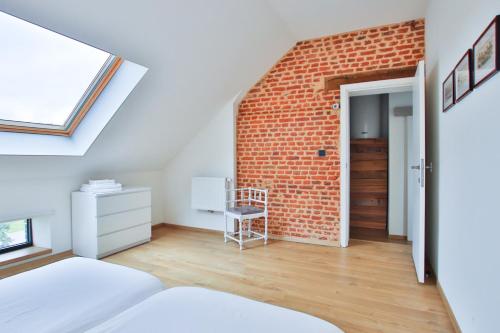 an attic bedroom with a brick wall at La Cense de Baudecet - Le Corps de Logis in Gembloux