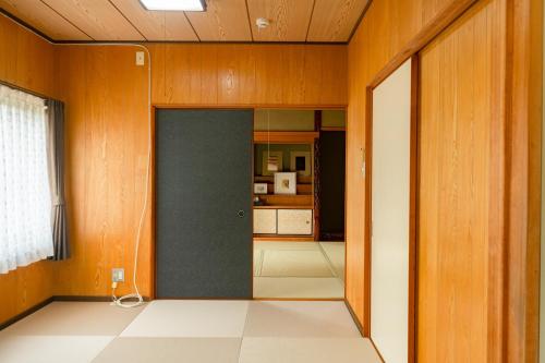 a hallway with a door in a room with a kitchen at とまばりゲストハウス in Sanuki