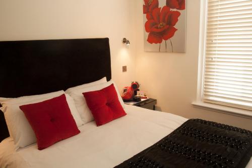 um quarto com uma cama branca e almofadas vermelhas em The Ship Leopard Boutique Hotel - No Children em Portsmouth