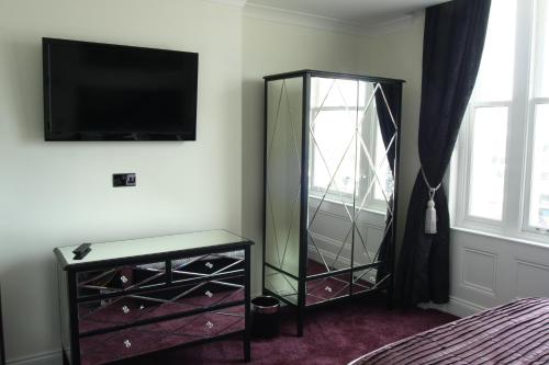a bedroom with a dresser with a mirror and a tv at The Ship Leopard Hotel - No Children in Portsmouth