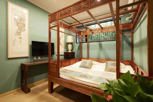 ein Schlafzimmer mit einem Himmelbett und einem TV in der Unterkunft Beijing Rong Courtyard Boutique Hotel in Peking