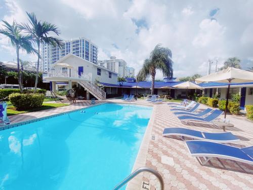 a large swimming pool with lounge chairs and umbrellas at Sea Steps By Lowkl in Pompano Beach