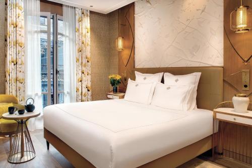 a bedroom with a large white bed and a window at La Demeure Montaigne in Paris