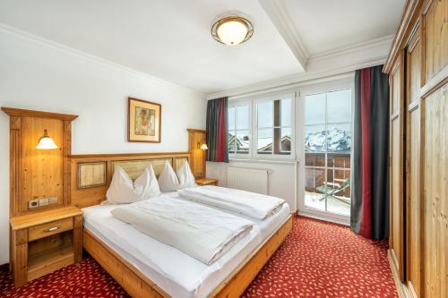 a bedroom with a large bed and a window at Hotel Almschlössl & Schrotteralm in Obertauern