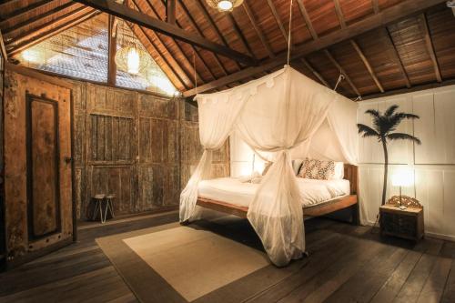 a bedroom with a bed with a mosquito net at Tropical Canggu Hostel in Canggu