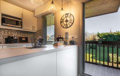 une cuisine avec un comptoir et une horloge au mur dans l'établissement Bord de mer C.L.S Deauville, à Benerville-sur-Mer