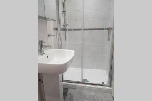 een witte badkamer met een wastafel en een douche bij St Ives self catering apartment private parking near beaches in St Ives