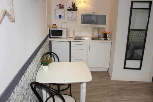 a small white kitchen with a table and chairs at Moderno apartamento en el corazón de Madrid Sol in Madrid