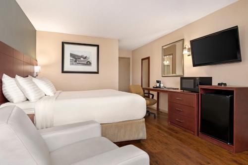 a hotel room with a bed and a flat screen tv at Days Inn by Wyndham Fredericton in Fredericton