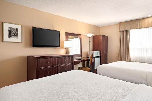 a hotel room with two beds and a flat screen tv at Days Inn by Wyndham Fredericton in Fredericton