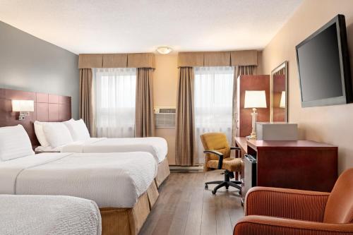 a hotel room with two beds and a desk at Days Inn by Wyndham Fredericton in Fredericton