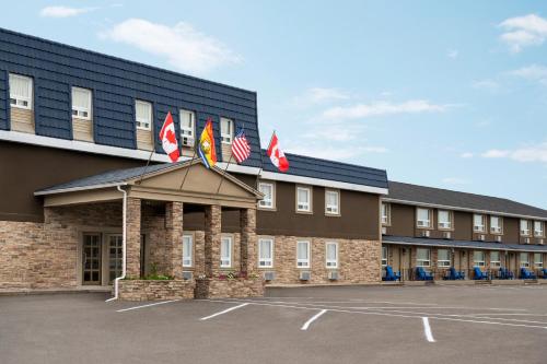 a hotel with flags on the front of a parking lot at Days Inn by Wyndham Fredericton in Fredericton