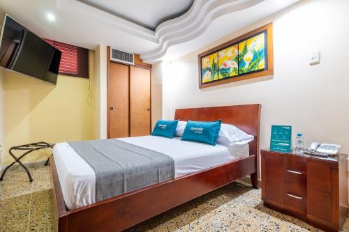 1 dormitorio con 1 cama con almohadas azules y TV en Ayenda Almirante, en Bucaramanga