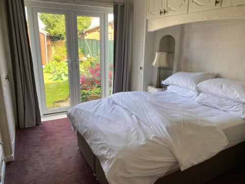 a bedroom with a large white bed and a window at The Corner Bungalow in Great Driffield