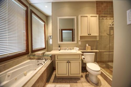 a bathroom with a toilet and a tub and a sink at Aiglon by Rendez-Vous Mont-Tremblant in Mont-Tremblant