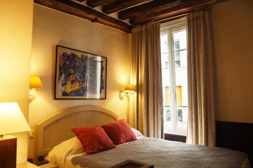 a bedroom with a bed with red pillows and a window at Hôtel du Cygne Paris in Paris