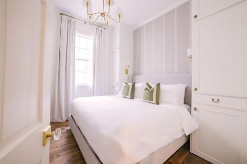 a white bedroom with a white bed and a chandelier at Guesthouse Charleston EAST 42 B in Charleston