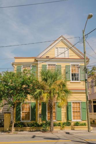 a yellow and green house with palm trees in front of it at Guesthouse Charleston EAST 42 B in Charleston
