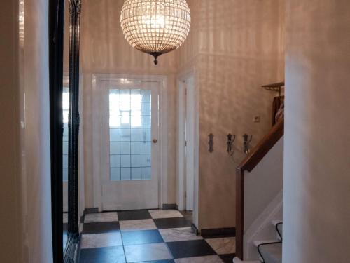 een hal met een deur en een kroonluchter bij Luxury Villa in Helmond with a Private Pool in Helmond