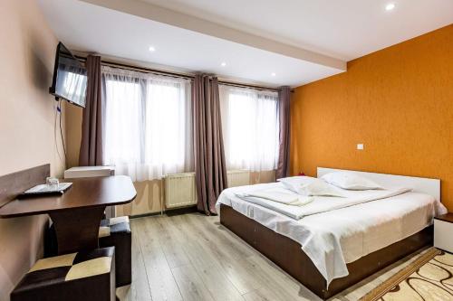 a bedroom with a bed and a desk and window at Casa Andy in Buşteni