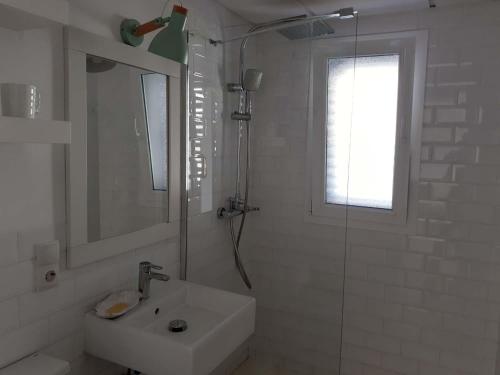 y baño blanco con lavabo y ducha. en Precioso Apartamento a 20 metros del mar, en Agua Amarga