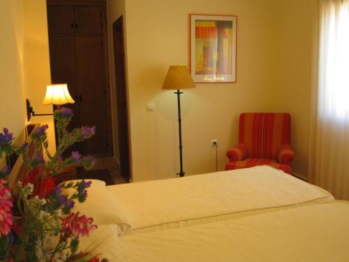 a bedroom with a bed and a red chair at Hotel Sindhura in Vejer de la Frontera