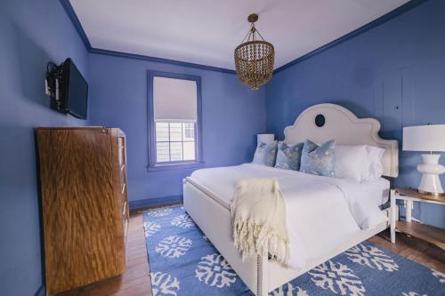 a blue bedroom with a white bed and a blue wall at Guesthouse Charleston EAST 42 C in Charleston