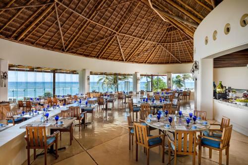 a restaurant with tables and chairs and the ocean in the background at Grand Velas Riviera Maya - All Inclusive in Playa del Carmen
