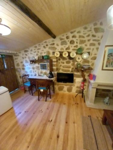 ein Wohnzimmer mit einem Tisch und einer Steinmauer in der Unterkunft Casa da Ti Maria Pereira in Monsanto