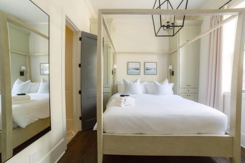 a bedroom with a large white bed and a mirror at Guesthouse Charleston EAST 46 E in Charleston