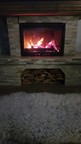 a brick fireplace with a fire in it at Vila Pestera in Peştera