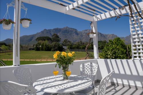 einen Tisch mit einer Blumenvase auf einer Terrasse in der Unterkunft Sunset Farm Stellenbosch in Stellenbosch